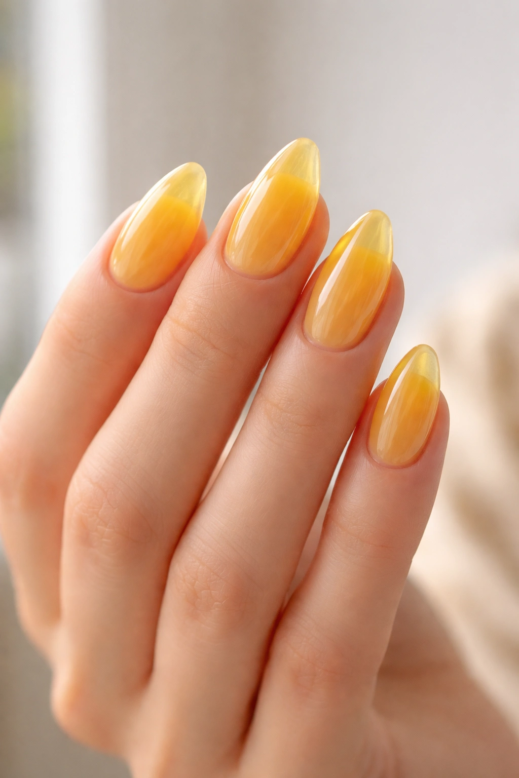 Close-up of short almond nails with yellow jelly translucent finish