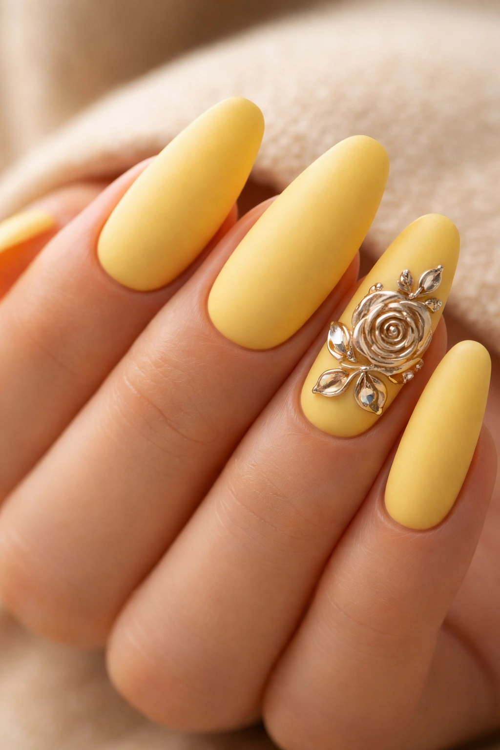Close-up of yellow matte acrylic nails with chrome rose accents in studio lighting
