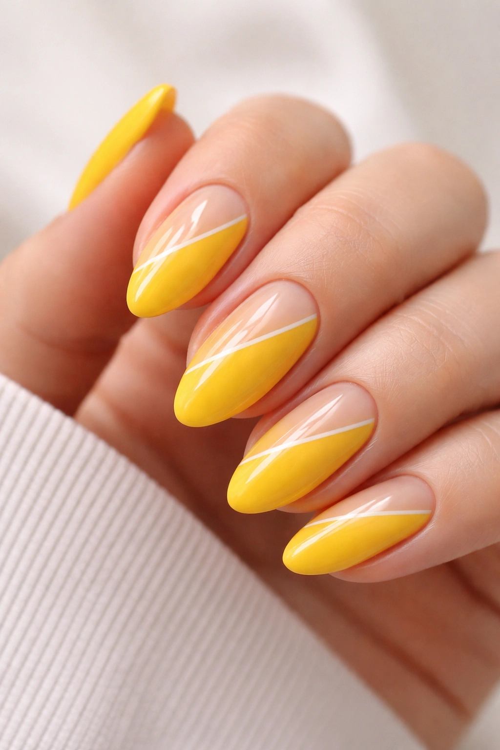 Close-up of bright yellow almond nails with a single negative-space line