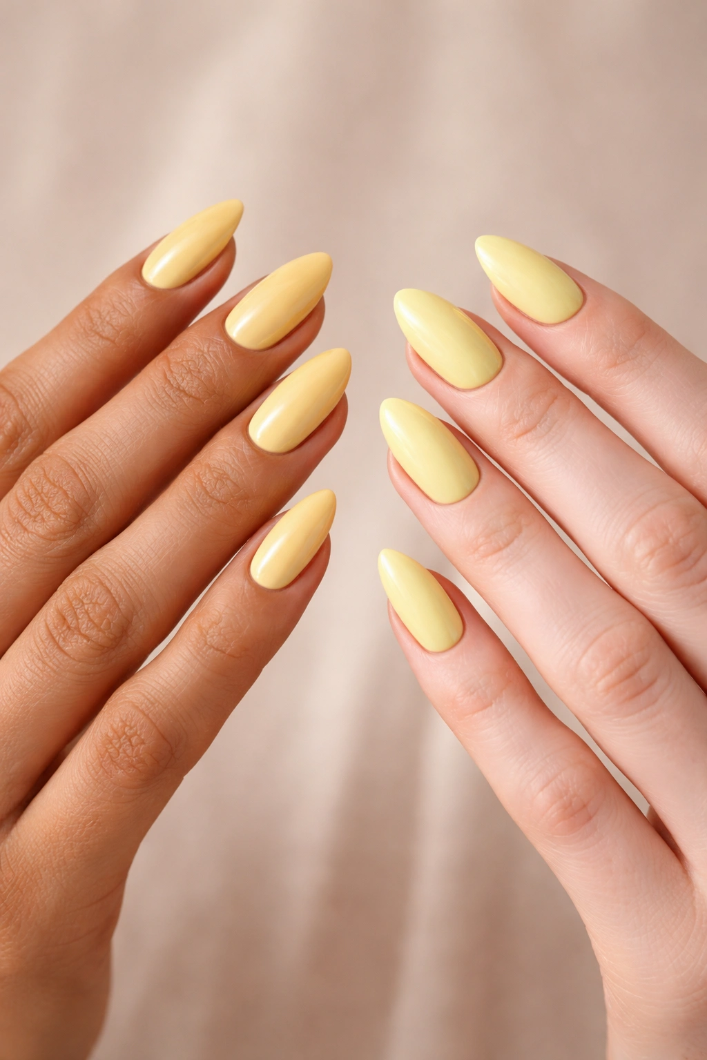 Two hands with almond nails in butter yellow and lemon yellow showing warm and cool tones