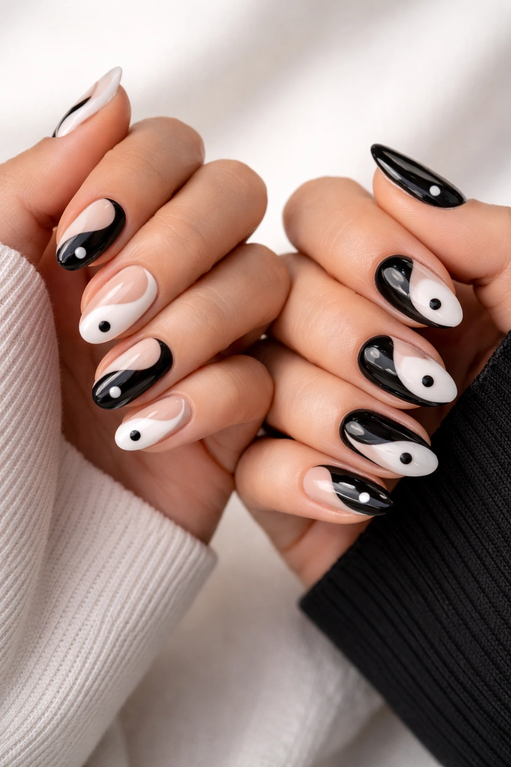 Two hands with yin-yang style negative space nails showing nude and colored accents