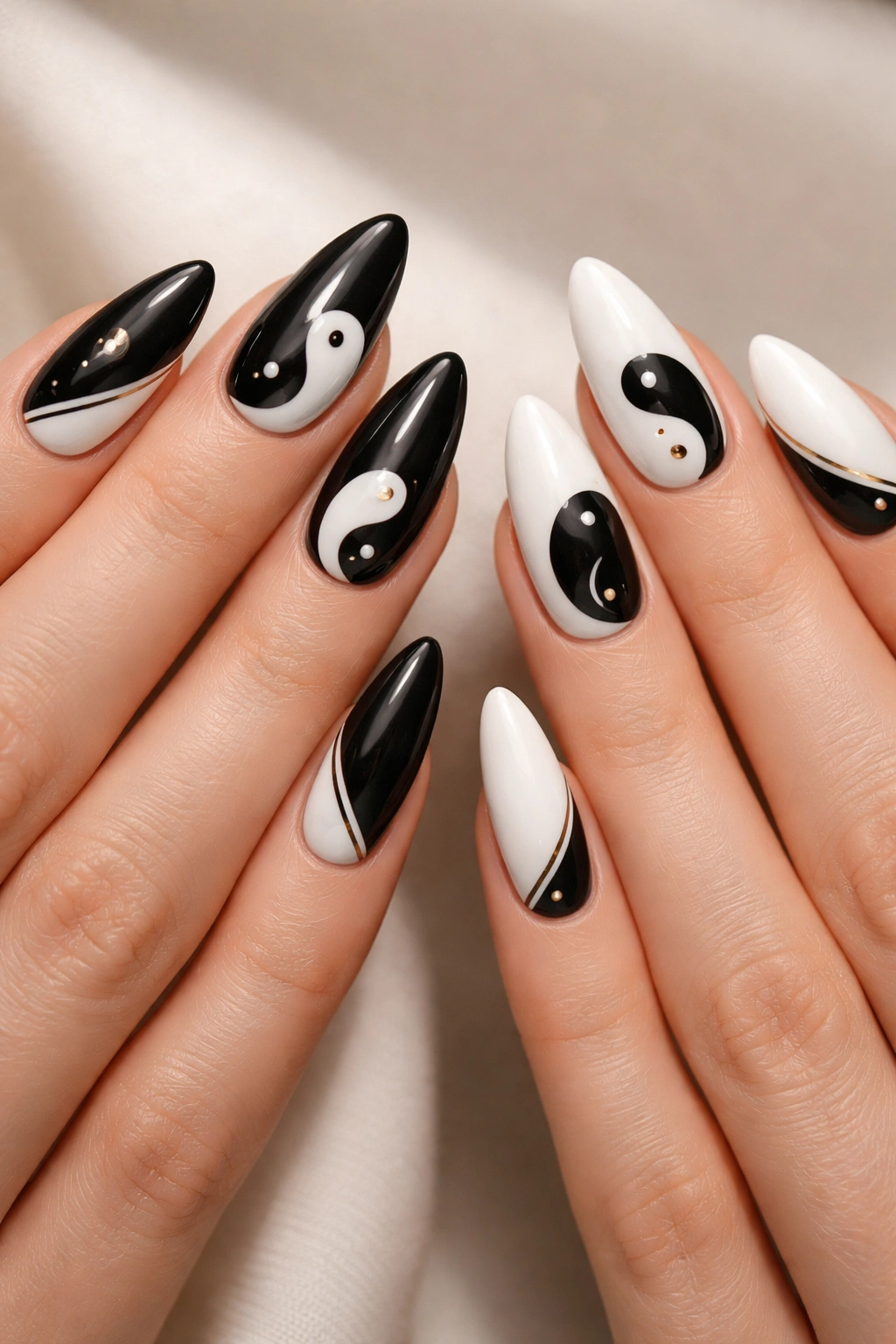 Two hands with almond nails in black and white yin-yang coordination with metallic accents