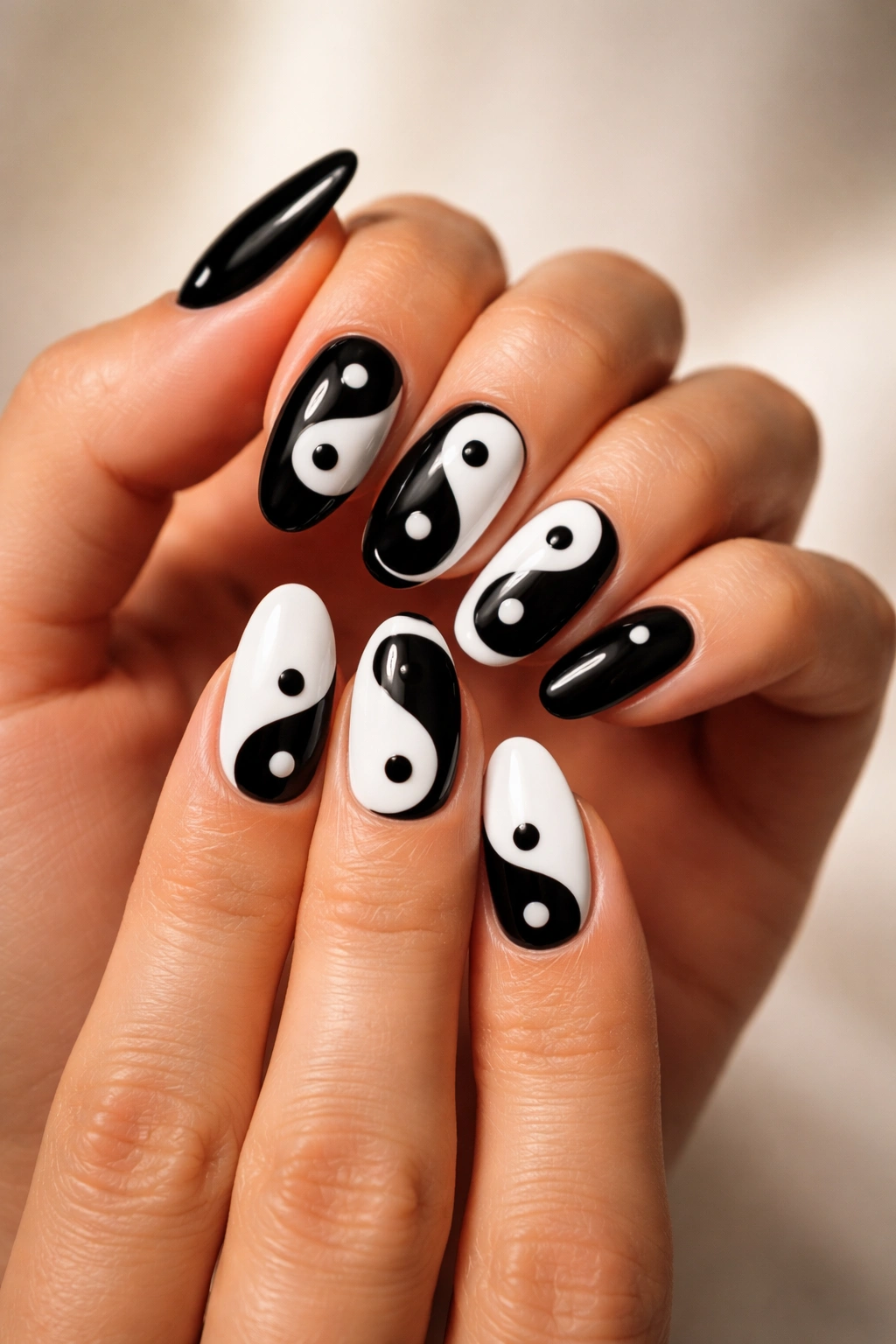 Two hands with yin-yang nail designs in black and white