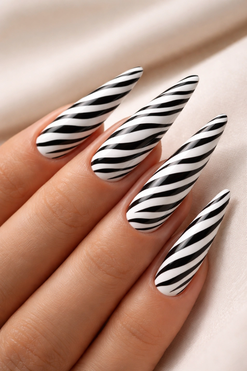 Close-up of stiletto nails with black and white zebra stripes on white base