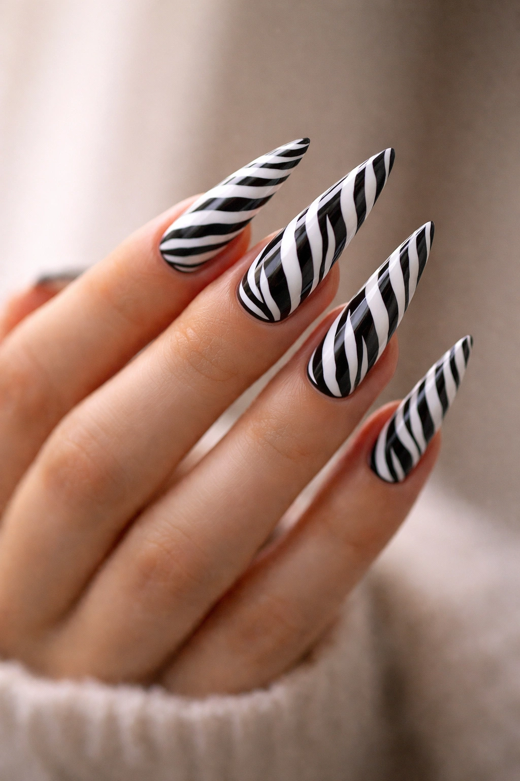 Close-up of zebra print stiletto nails on a hand against a neutral background
