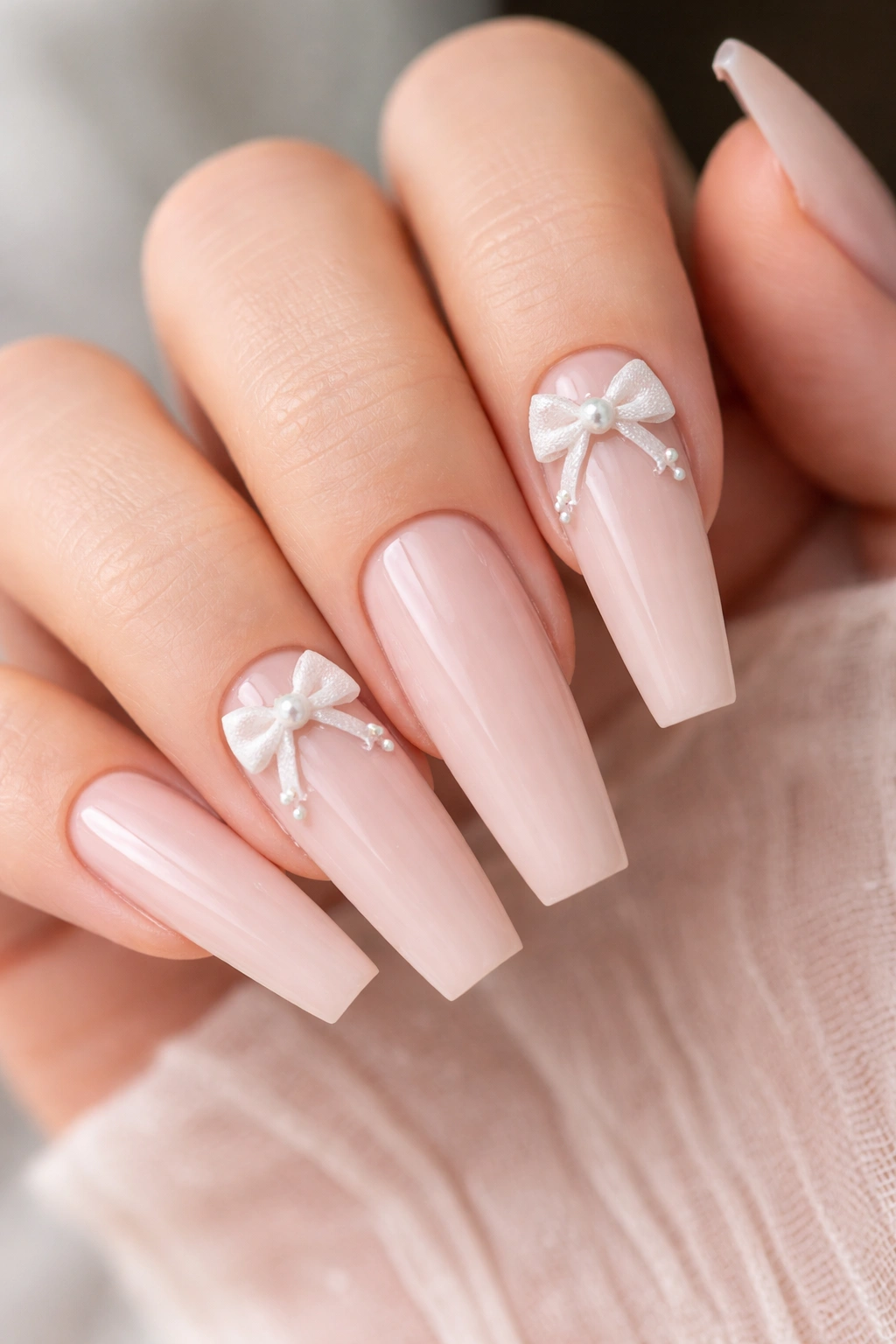 Close-up of 3D bow coffin nails with pearl details on a nude base