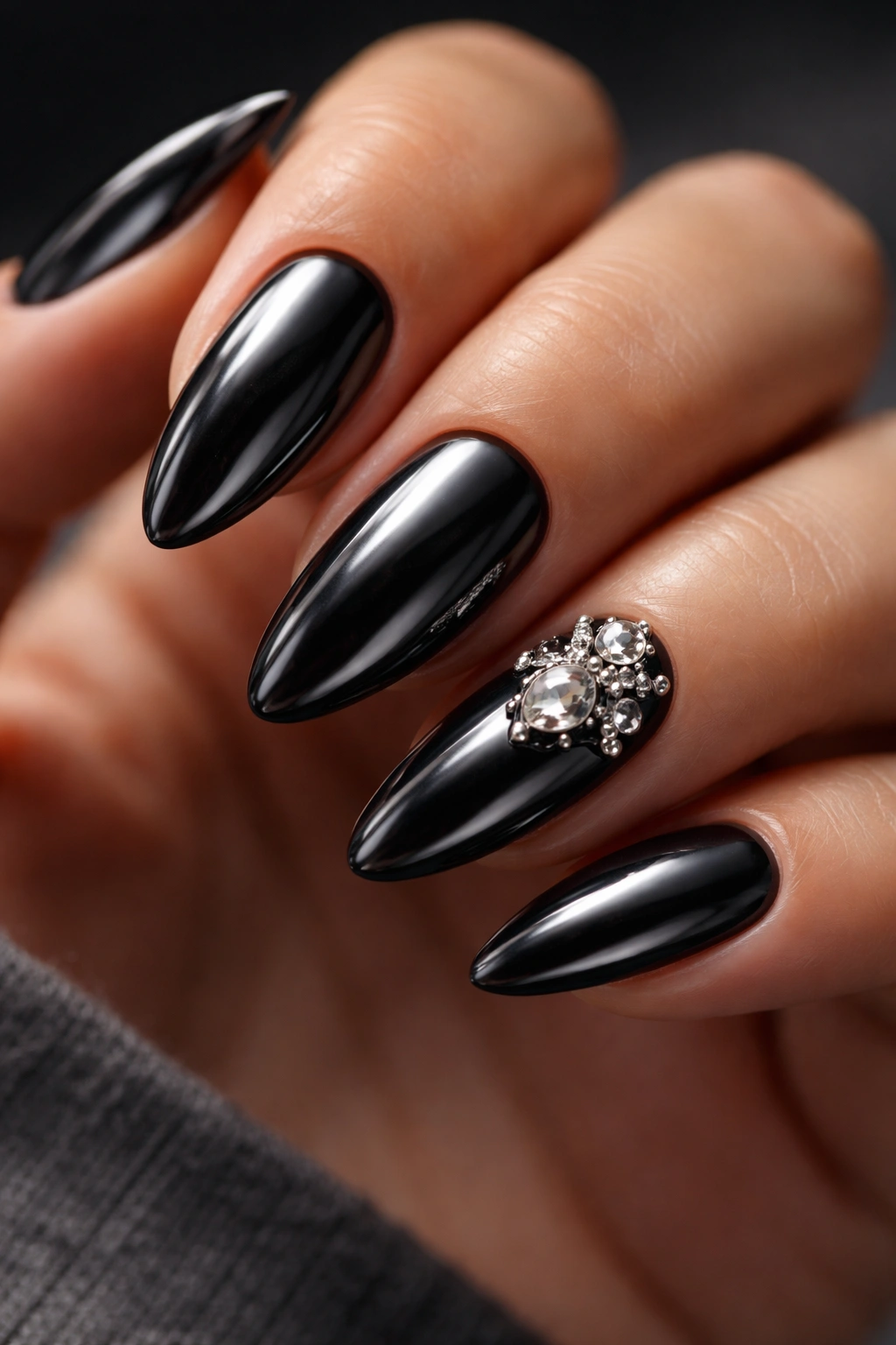 Almond nails with a small 3D charm accent on the black chrome base