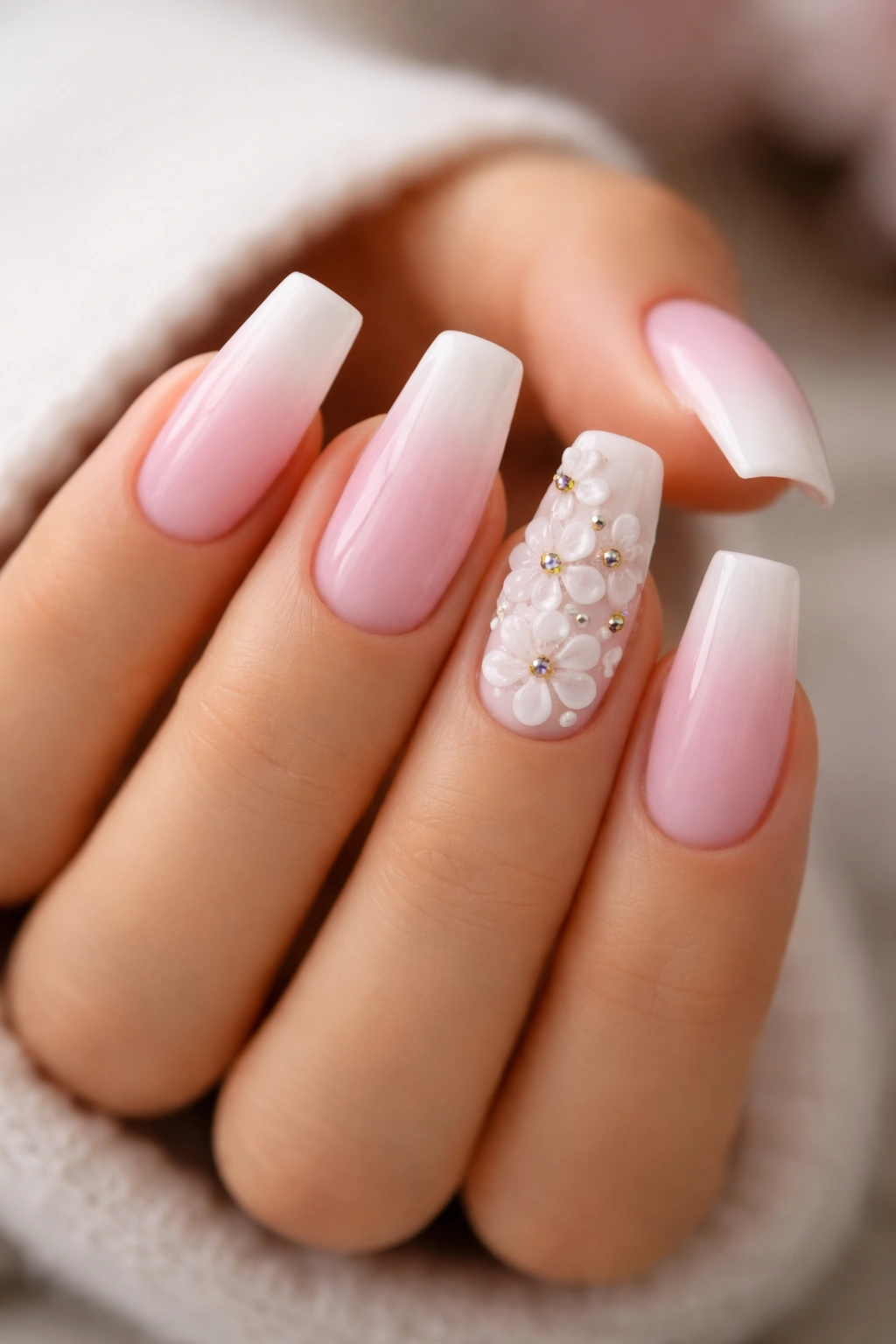 Close-up of pink-white ombre coffin nails with 3D flowers on two accent nails