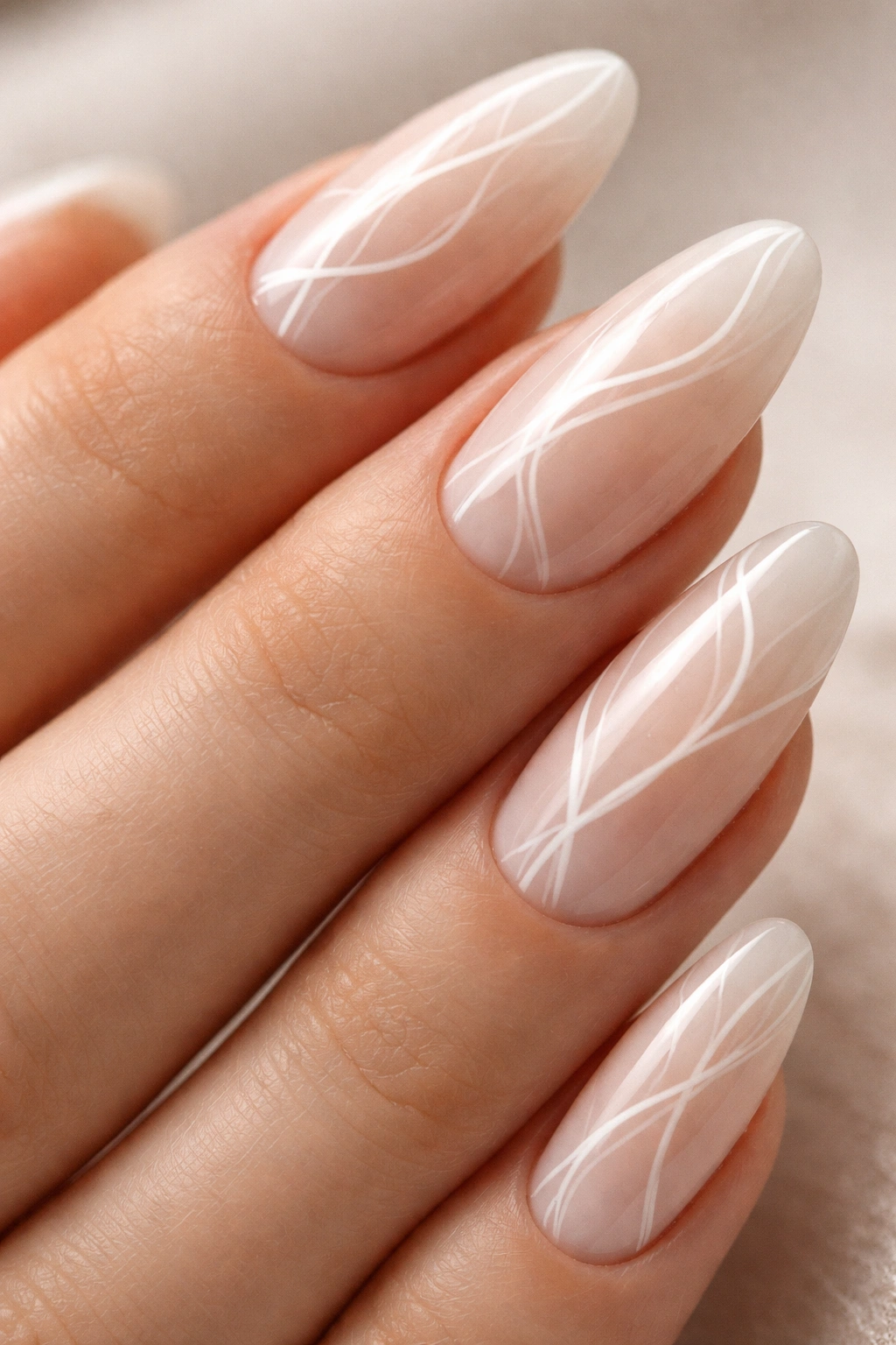 Close-up of almond nails with abstract white line art on a milky nude base