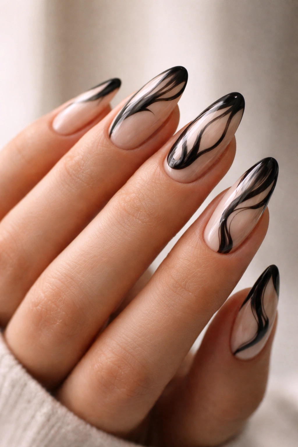 Almond nails with sheer base and abstract black swirls