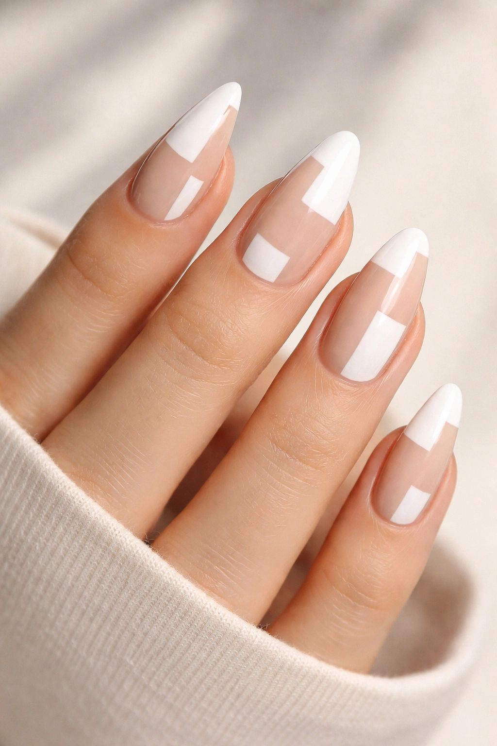 Close-up of nude almond nails with irregular white block shapes