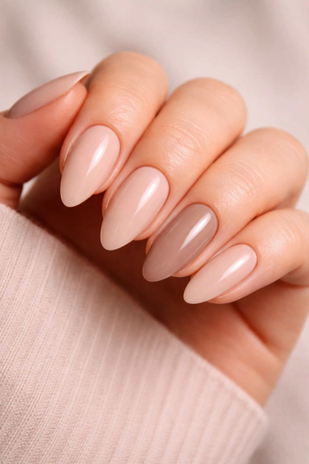 Almond manicure with nine nude nails and one accent nail in deeper beige
