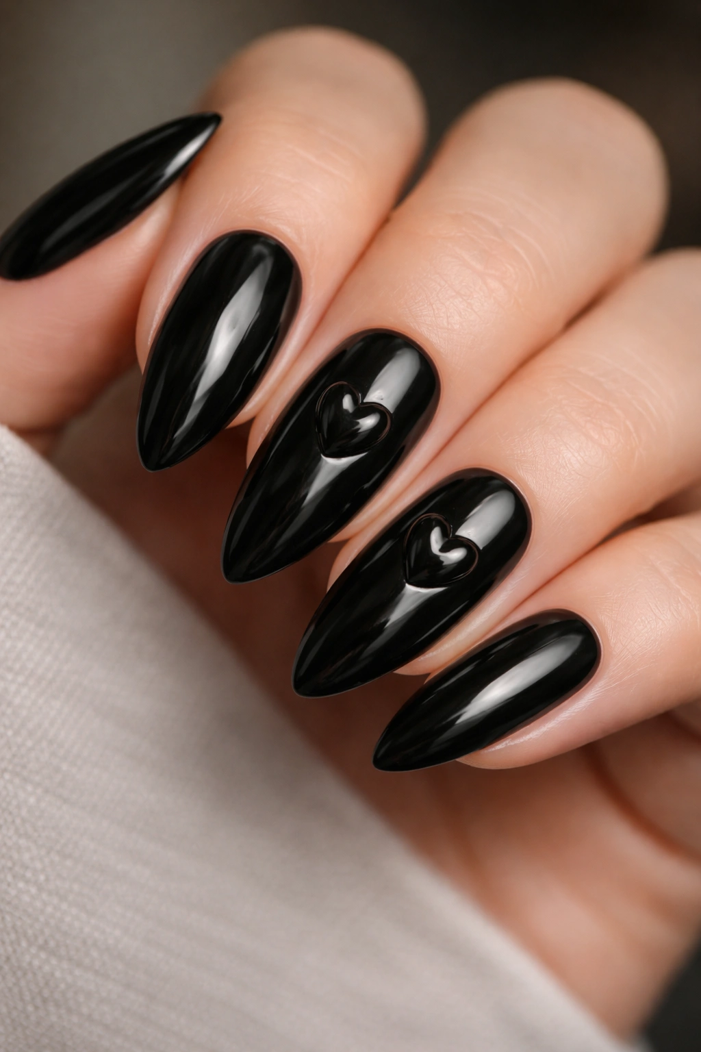 Close-up of black almond nails with raised glossy hearts