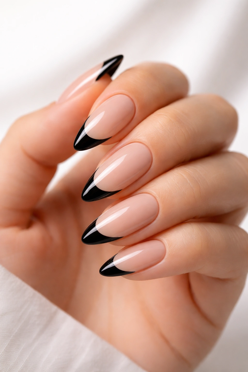 Close-up of almond nails with black French tips on nude base