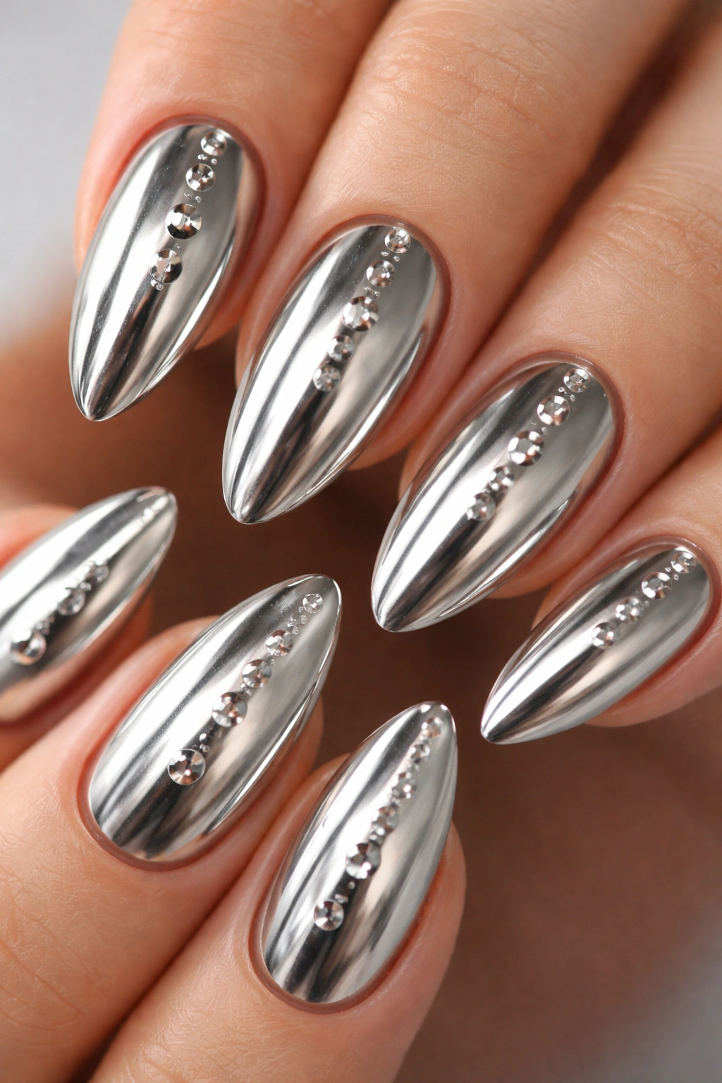 Close-up of almond nails with chrome finish and gel droplets