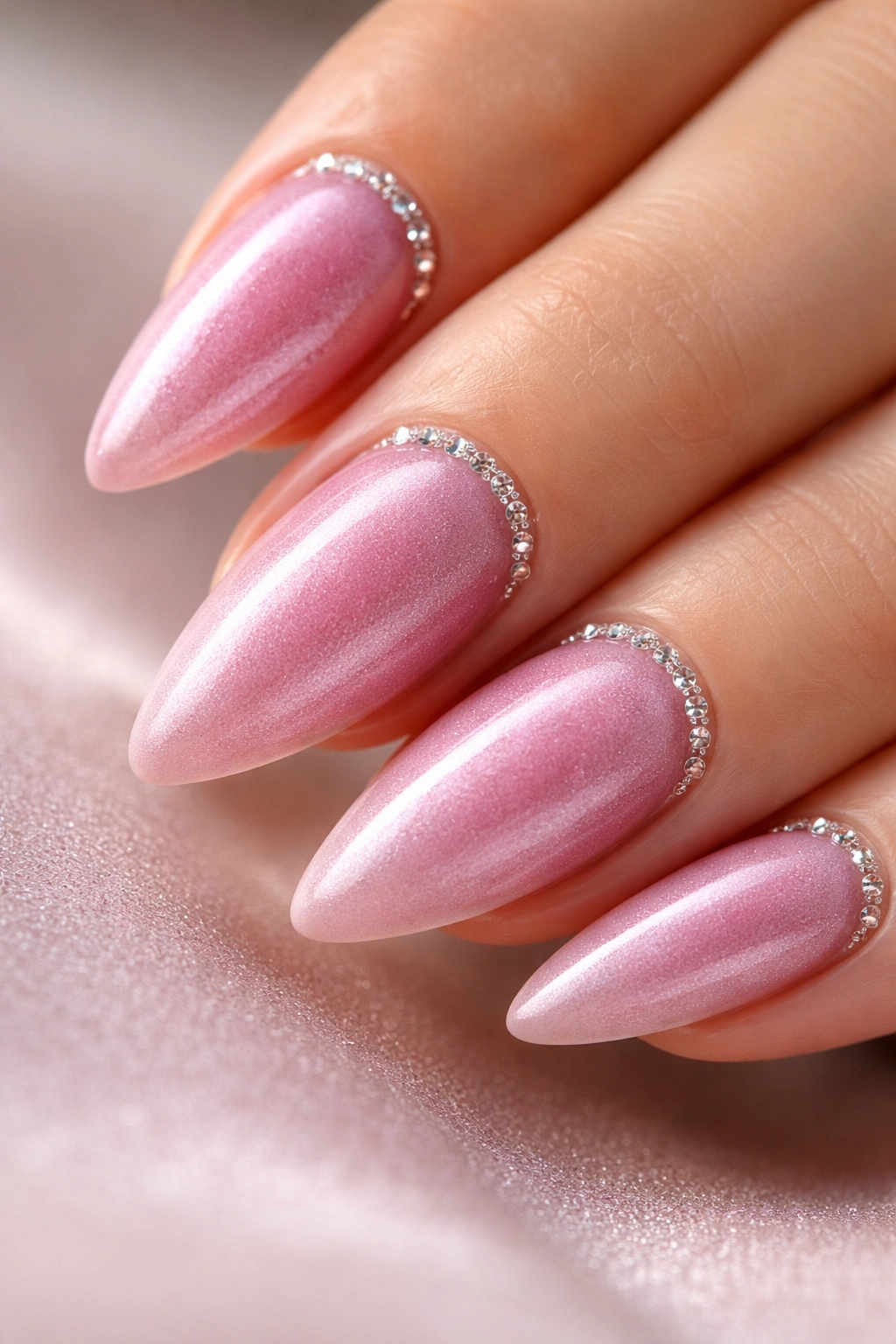 Close-up of almond nails with pink velvet finish and crystal cuticle line