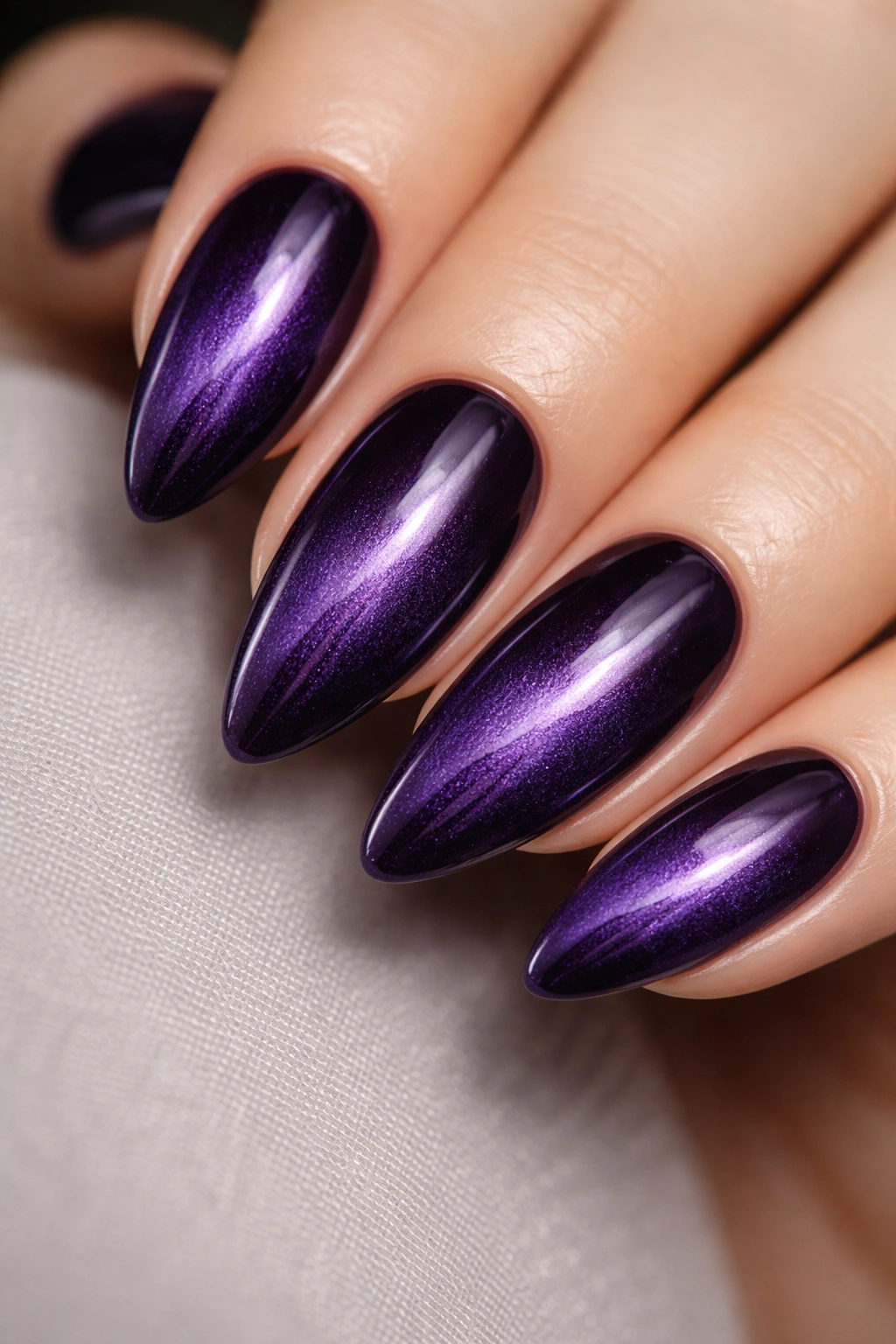 Amethyst cat-eye almond nails with dark center magnetic stripe.