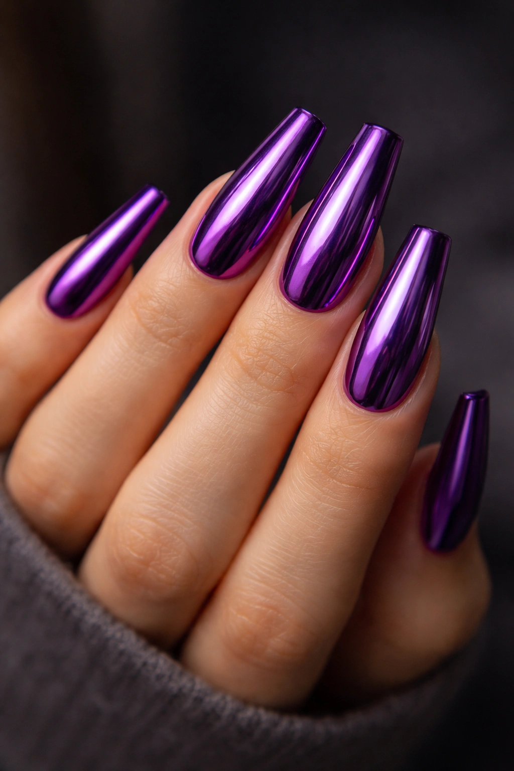 Hand with amethyst chrome coffin nails reflecting light in a mirror finish