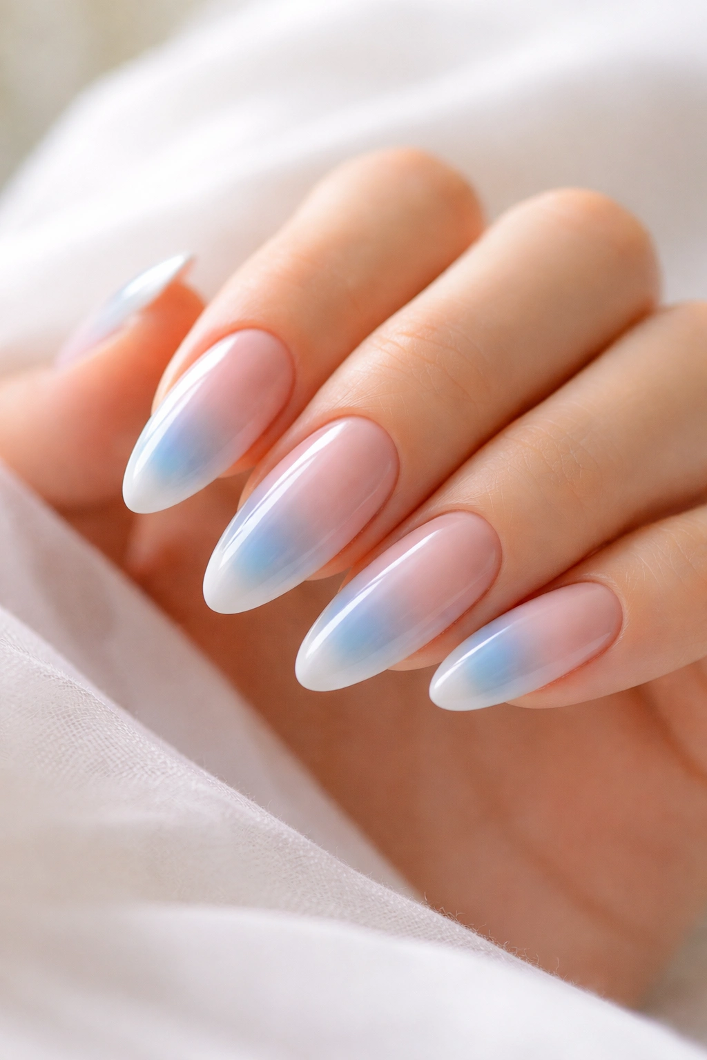 Aura blue French tips with soft gradient on almond nails.