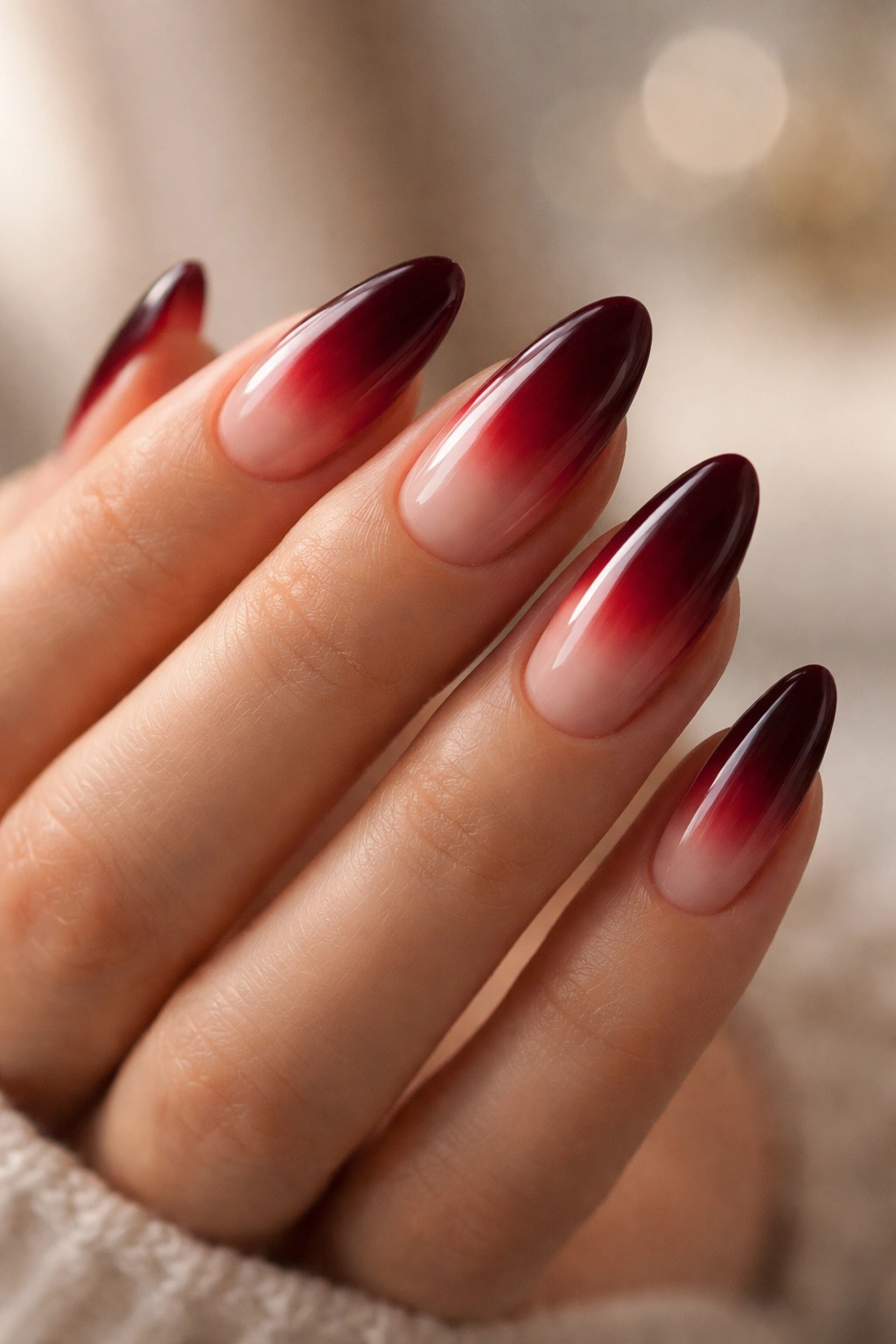 Almond nails with a soft red aura glow over nude base.