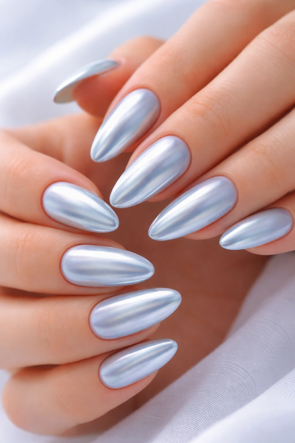Close-up of baby blue chrome almond nails on pale base