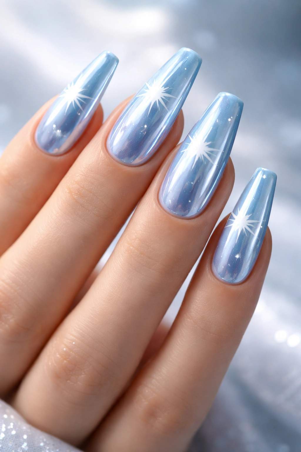 Close-up of baby blue chrome coffin nails with white starburst patterns