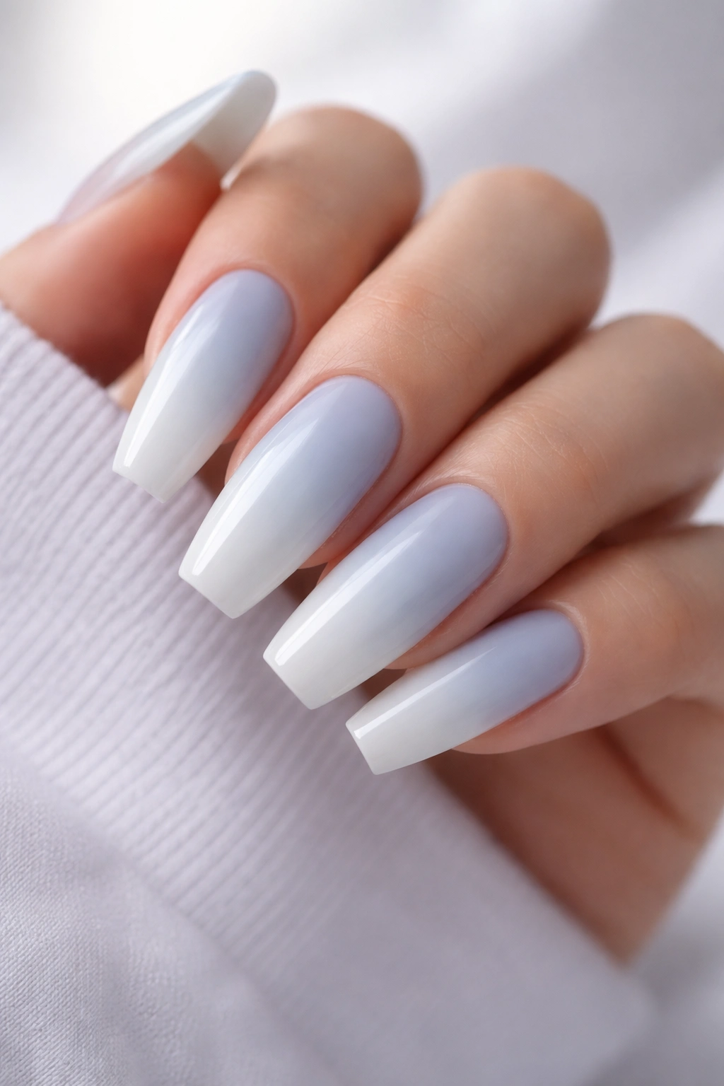 Close-up of baby blue to cloud white coffin nails with glossy finish