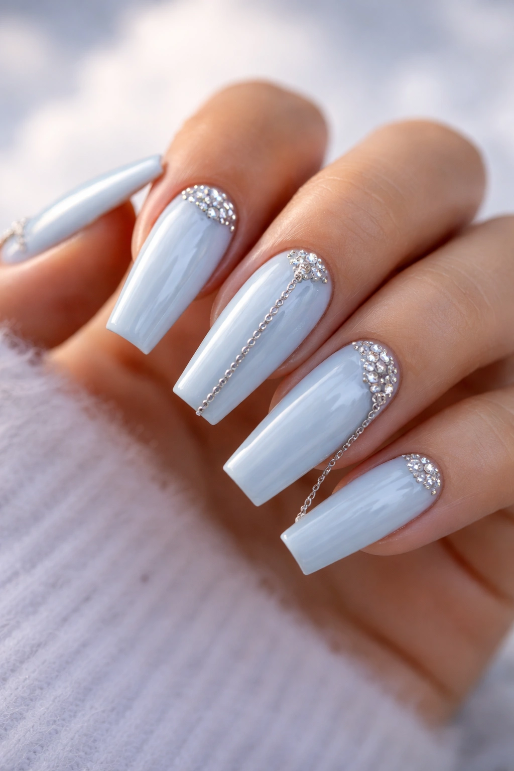 Baby blue coffin nails with silver chains and stones on a soft background