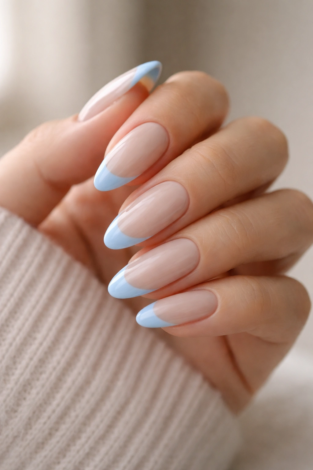 Milky nude almond nails with opaque baby blue tips in a close-up