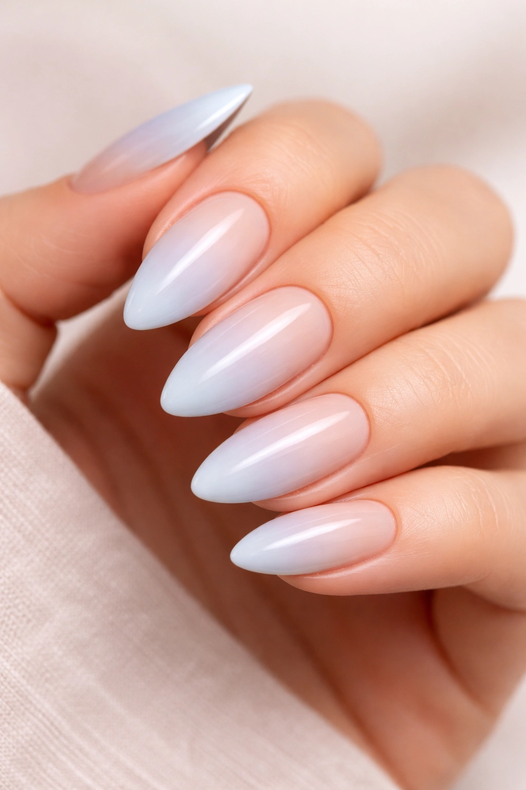 Close-up of almond nails with baby blue ombre fading into nude