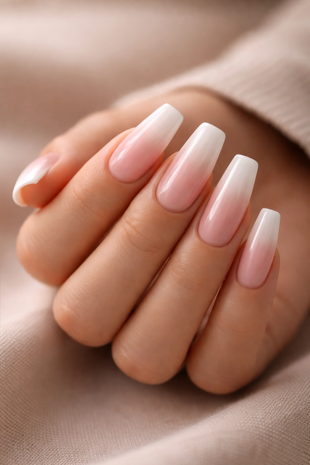 Close-up of baby boomer coffin nails with pink-nude to milky white ombré
