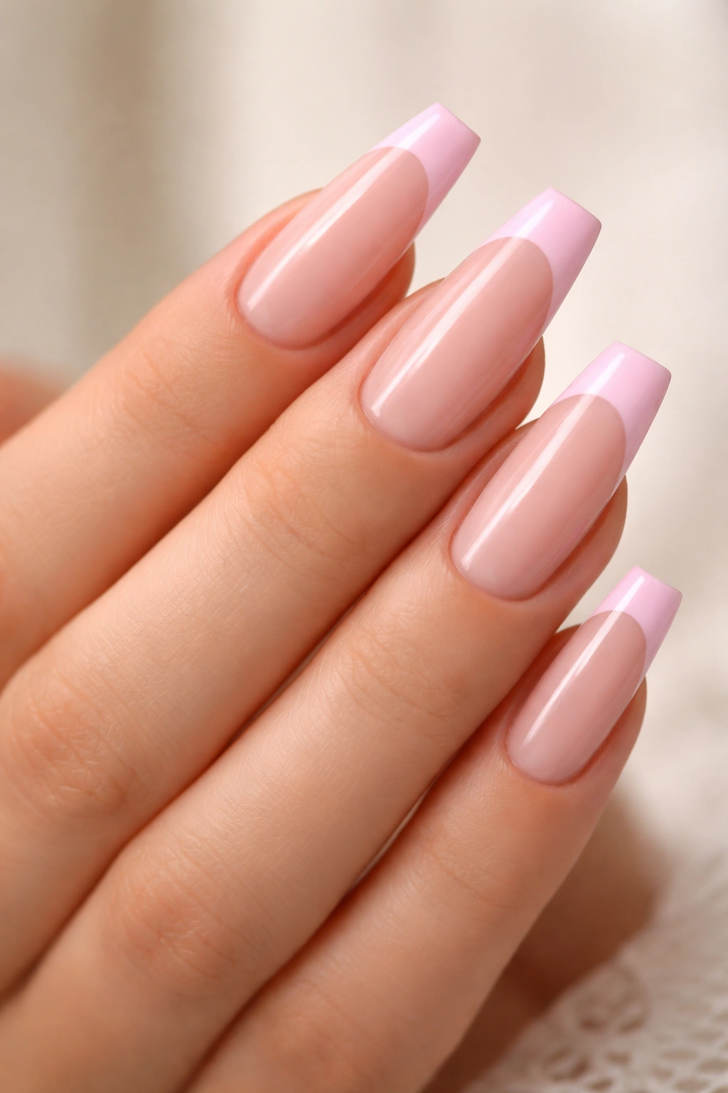 Close-up of baby pink French tip coffin nails with sheer base