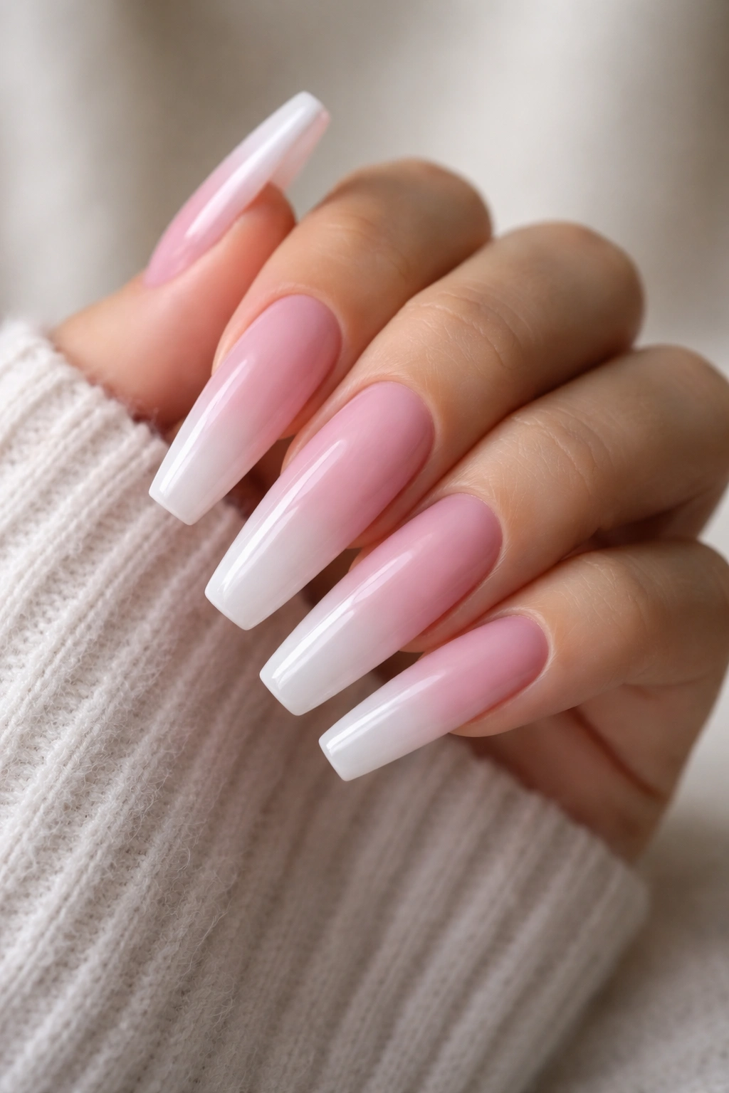 Soft pink to white ombré coffin nails on a hand