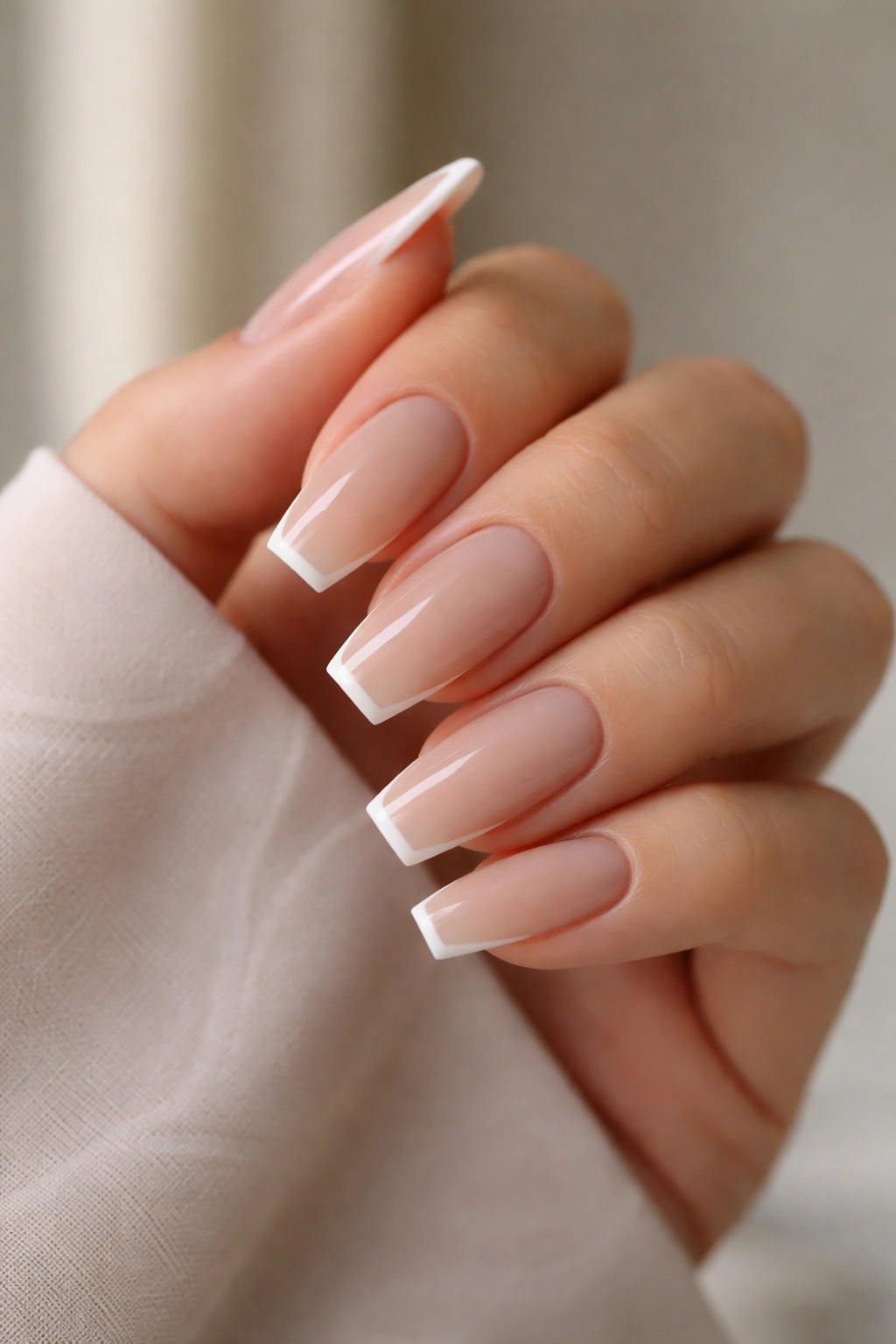 Soft beige coffin nails with ultra-thin white tips in a clean micro-French style