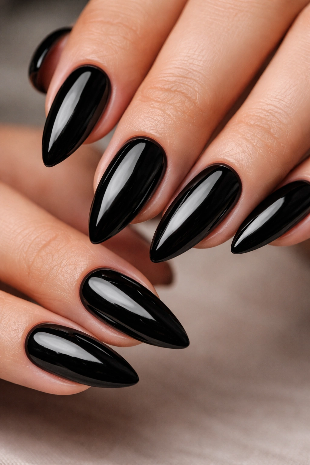 Close-up of high-gloss jet-black almond nails with mirror finish