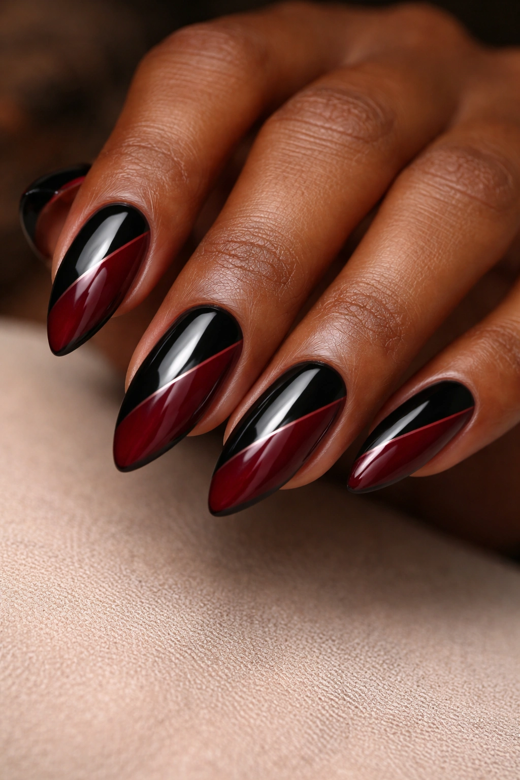 Close-up of black and burgundy split nails on almond shapes