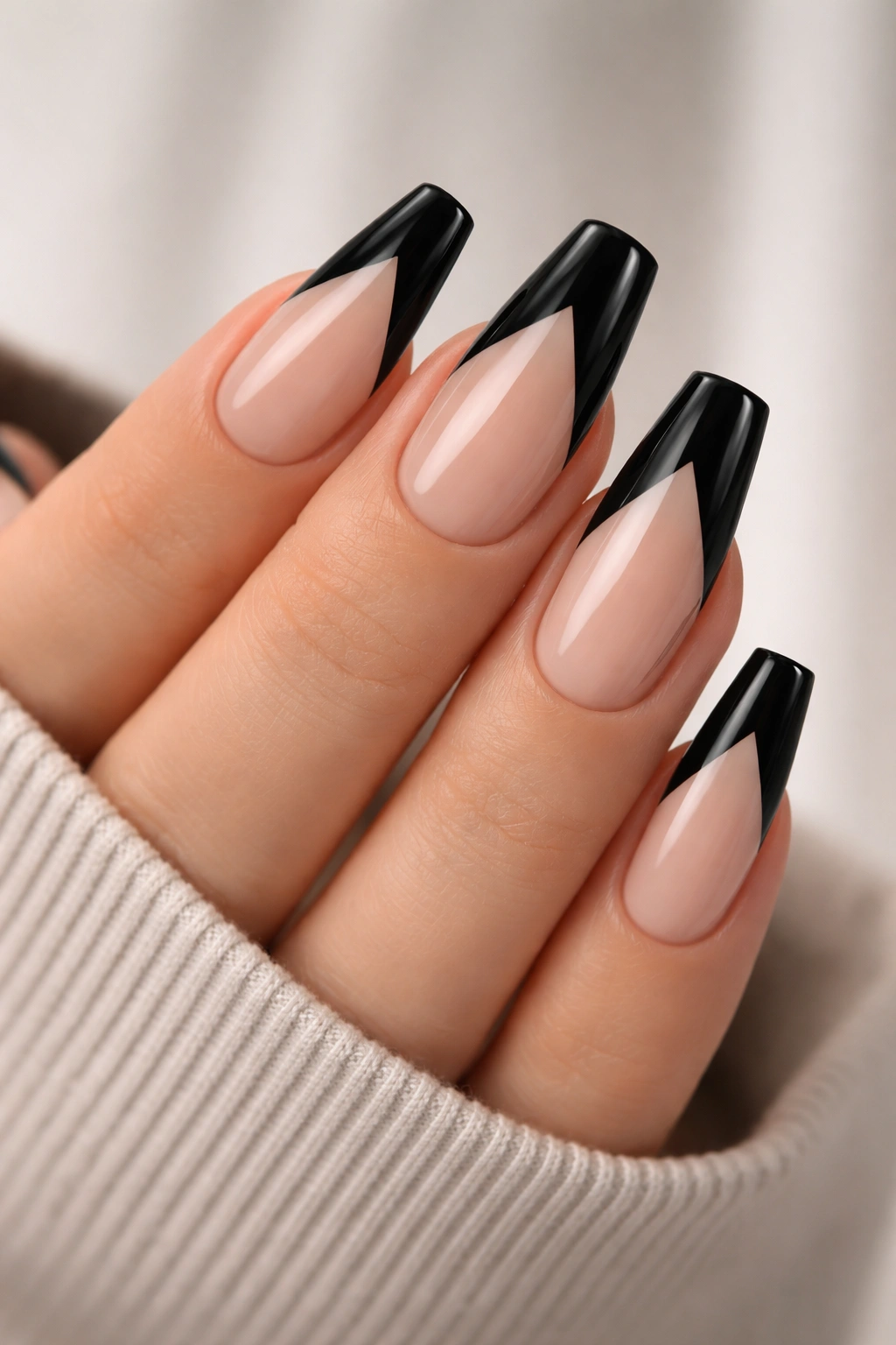 Close-up of medium-length coffin nails with a black negative-space chevron on a sheer base