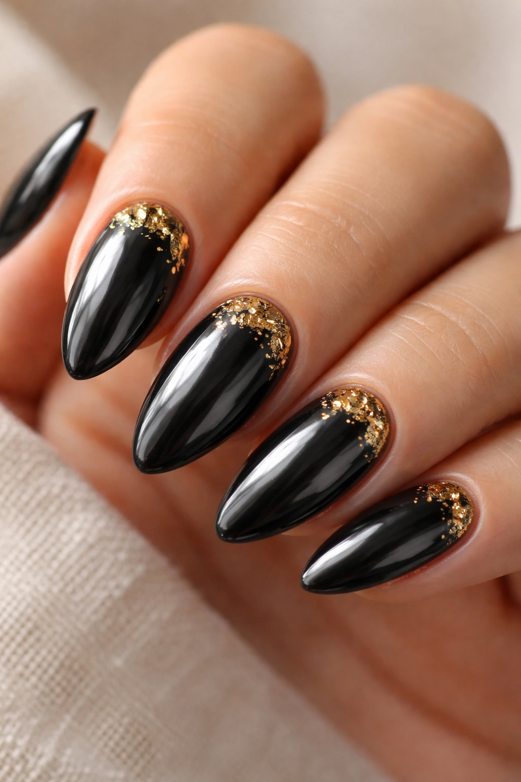 Almond nails with black chrome and gold foil flecks for luxe accent