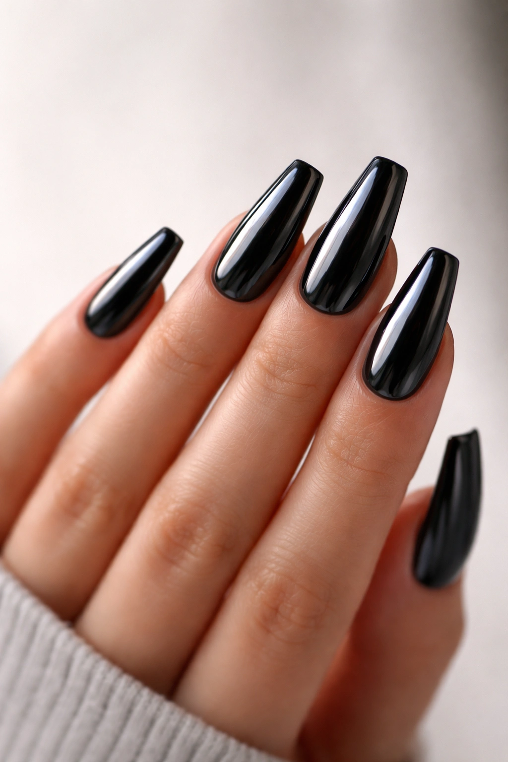 Close-up of black chrome coffin nails with mirror finish on a hand
