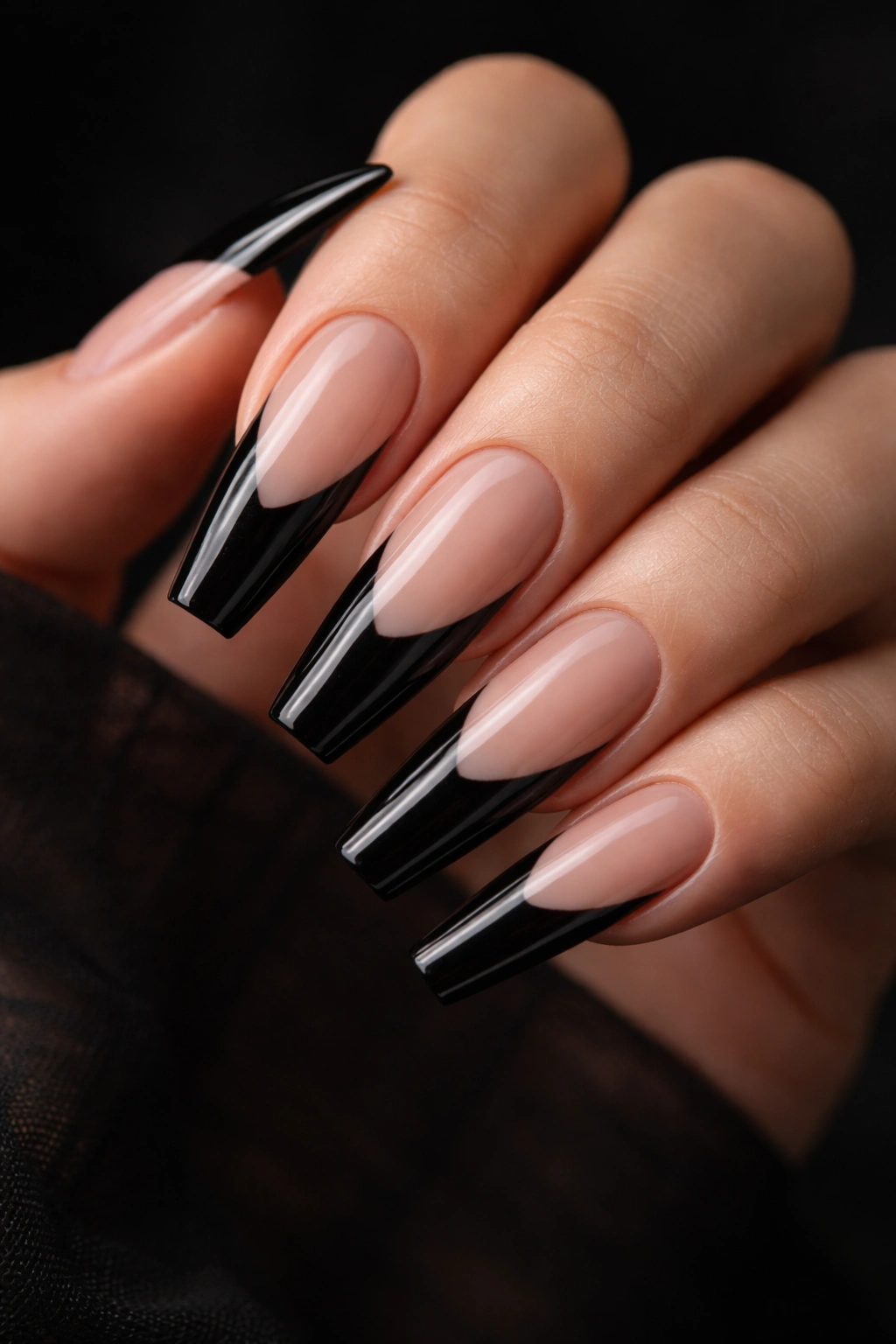 Close-up of black French coffin nails with deep smile line on a hand against dark background