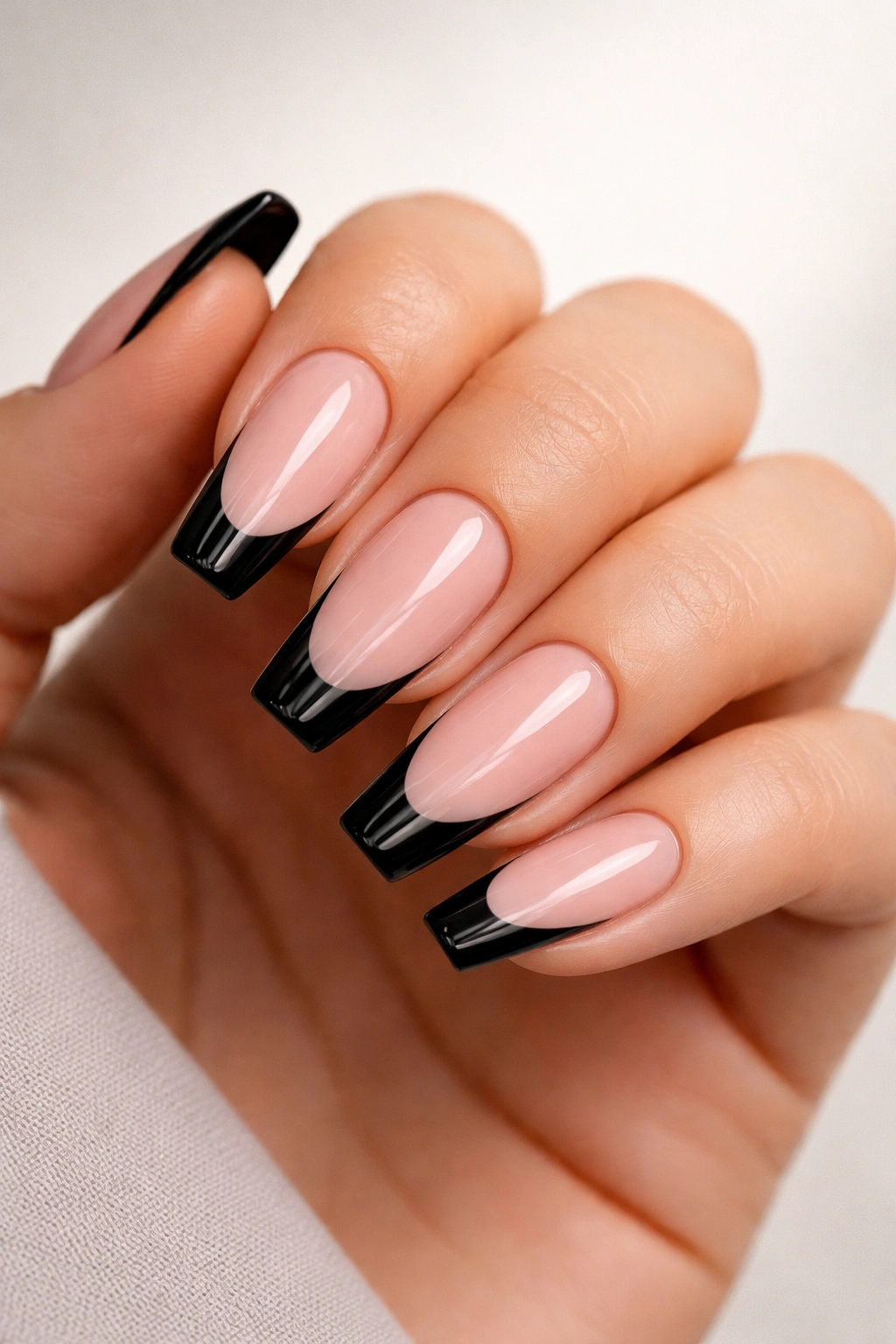 Close-up of medium coffin nails with nude base and glossy black tips.