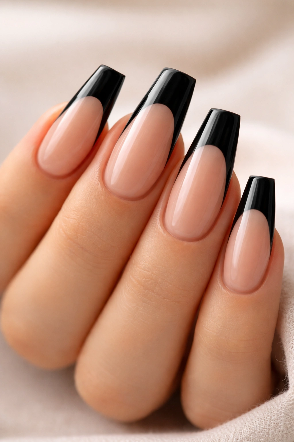 Black French tip coffin nails on a sheer nude base with black tips
