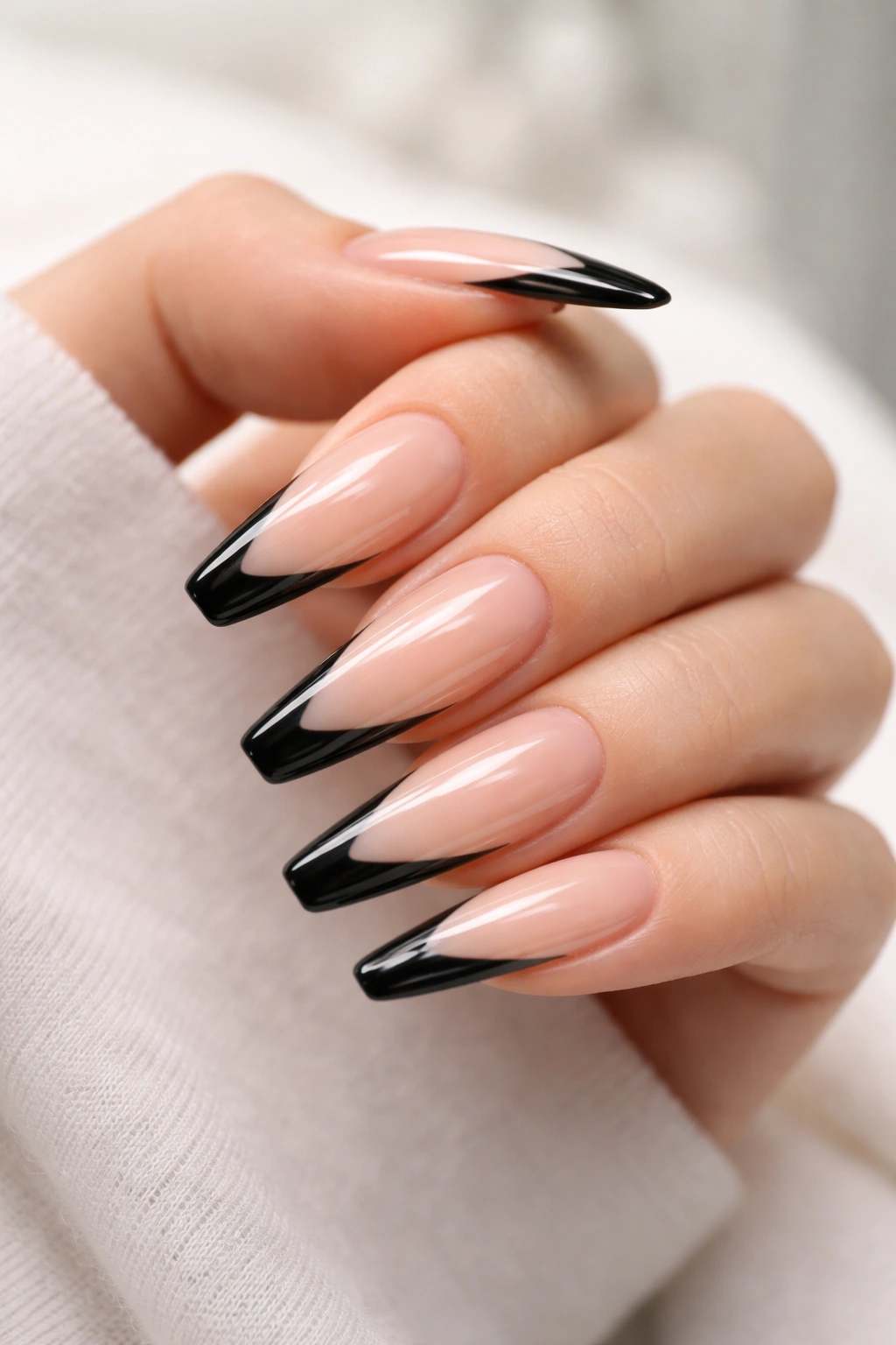 Close-up of long coffin nails with a narrow side-swept black French tip on a sheer nude base.