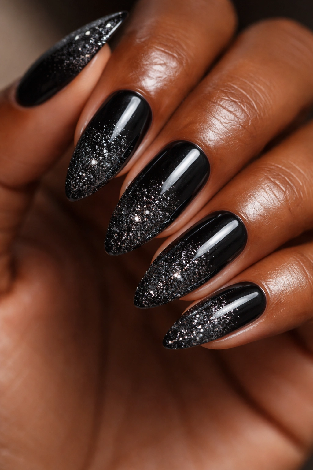 Close-up of black nails with glitter gradient at tips