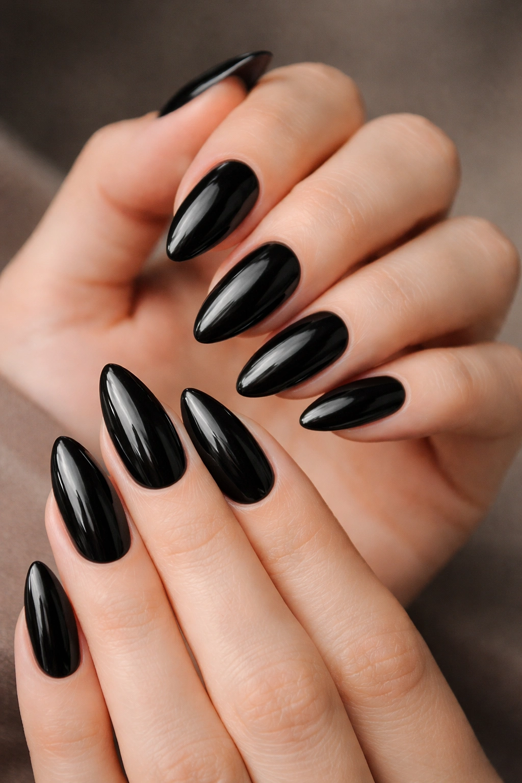 Close-up of hands with black almond nails in glossy finish.