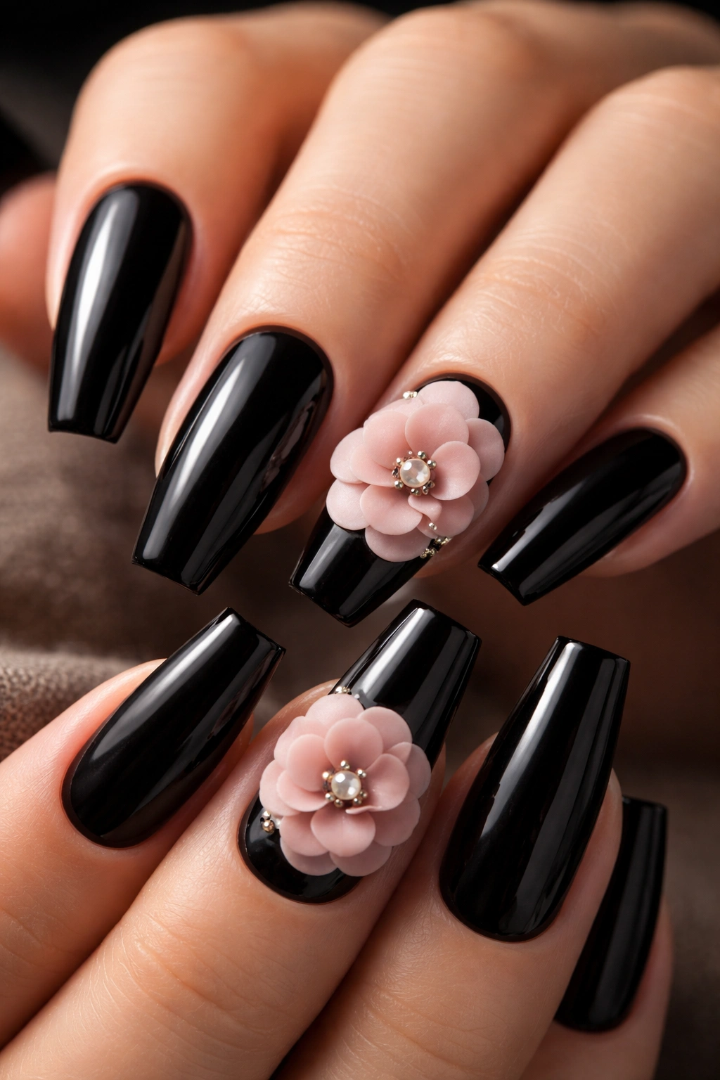 Close-up black coffin nails with blush camellias on select nails.