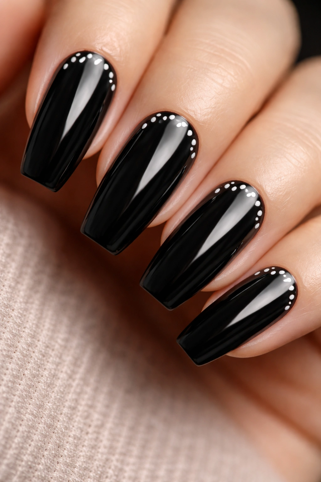 Glossy black coffin nails with white crescent dots forming a curved arc.