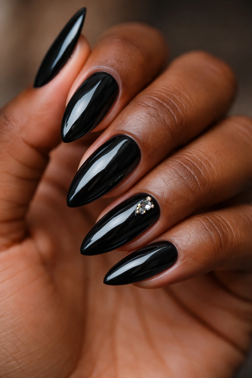 Black almond nails with subtle gemstone accents on an accent nail