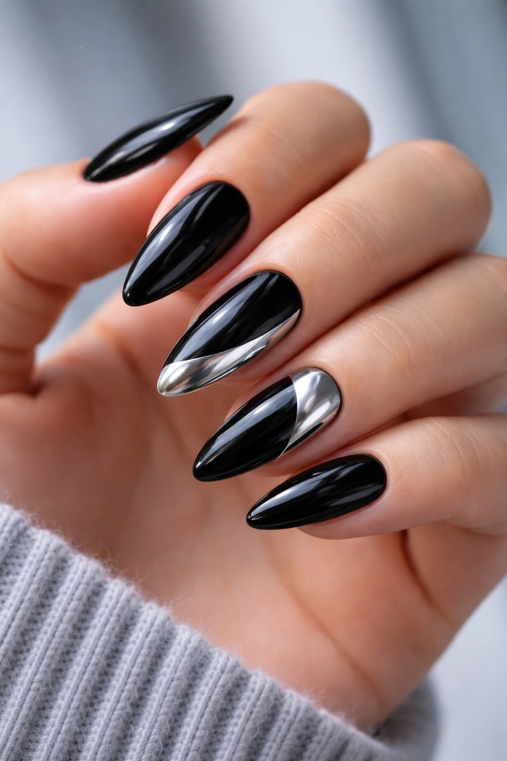 Close-up of black almond nails with silver chrome accents on two nails