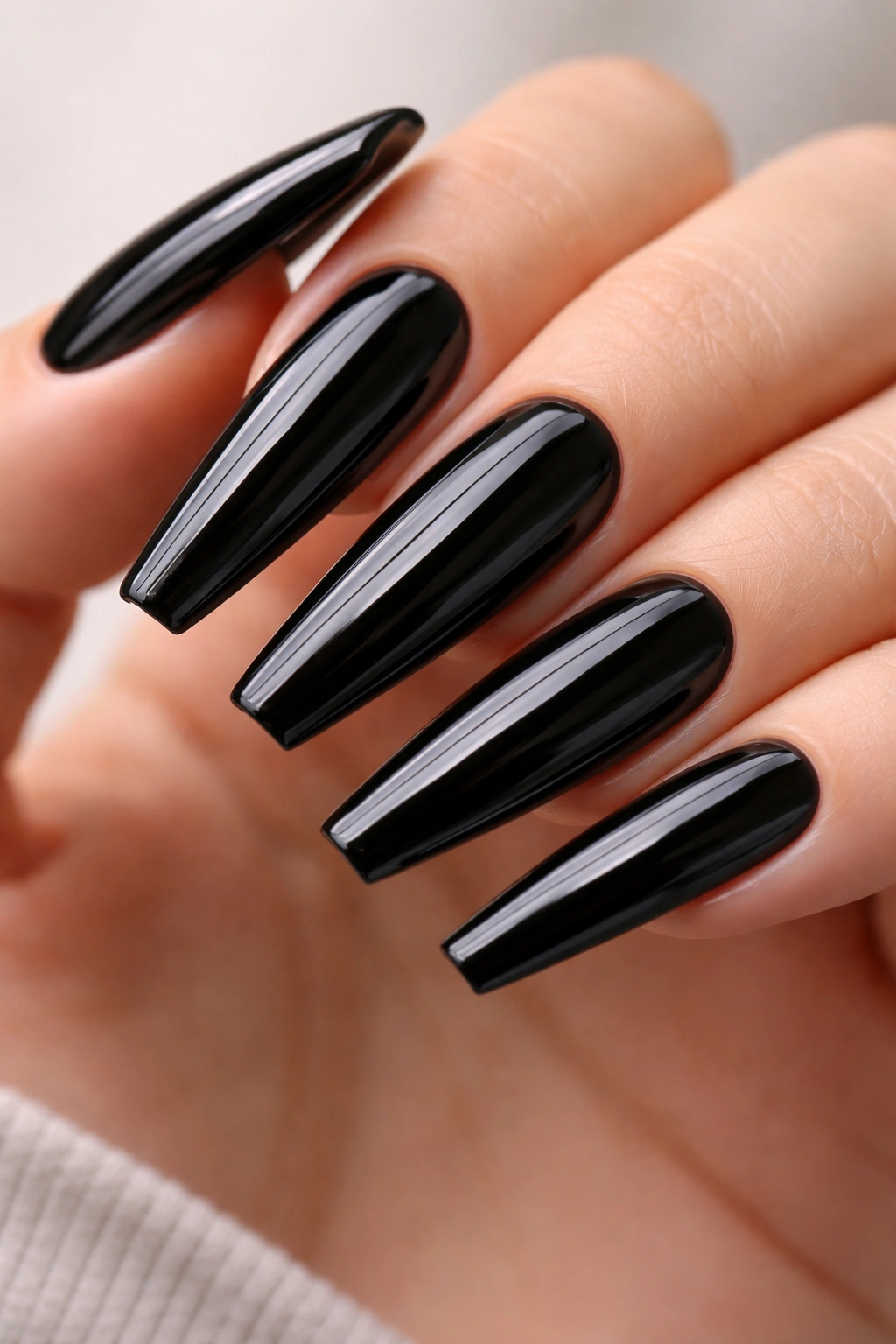Close-up of long coffin nails with glossy black patent finish